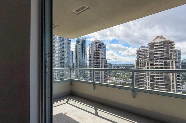 Bright bedroom with purple floral bedspread, pink ruffled pillows, and city view through vertical blinds. - 1805-4388 Buchanan Street, Burnaby