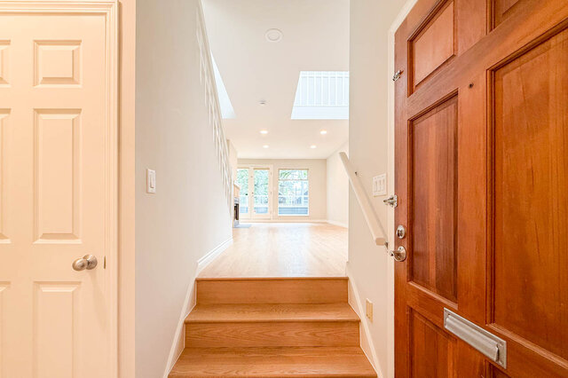 Bright living area with hardwood floors and a wooden deck view through French doors. - 3443 West 6th Ave, Vancouver West Side