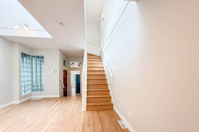 Bright living area with large bay windows overlooking lush backyard and tiled flooring. - 3443 West 6th Ave, Vancouver West Side