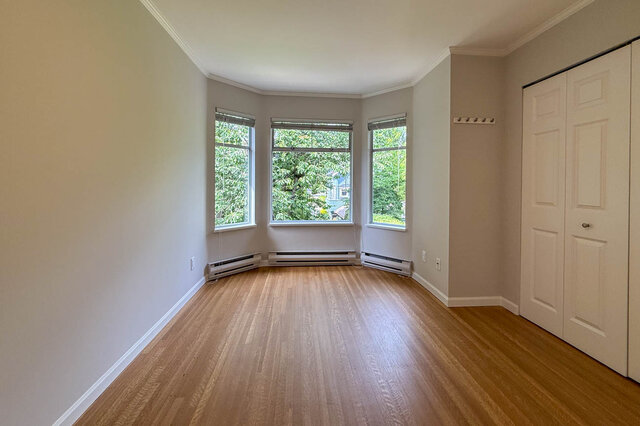 Bright bedroom with hardwood floors and bay window overlooking lush greenery. - 3443 West 6th Ave, Vancouver West Side