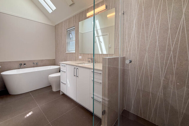 Modern bathroom with glass shower enclosure and adjacent hardwood-floored living. - 3443 West 6th Ave, Vancouver West Side