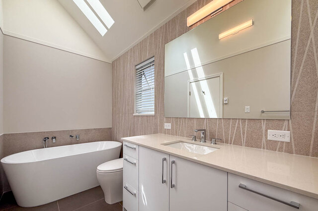 Modern bathroom with freestanding tub and sleek white vanity. - 3443 West 6th Ave, Vancouver West Side