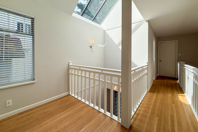 Well-lit stairwell with white railings and warm hardwood floors. - 3443 West 6th Ave, Vancouver West Side