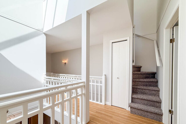 Bright stairwell landing with white railings and hardwood floors. - 3443 West 6th Ave, Vancouver West Side