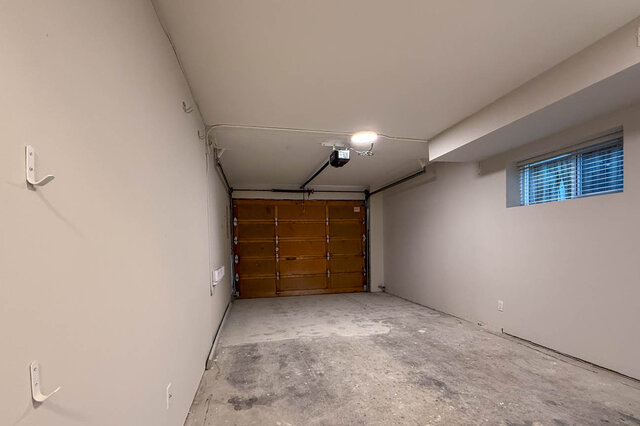 a garage with concrete floor, wooden overhead door, small window, and wall hooks - 3443 West 6th Ave, Vancouver West Side