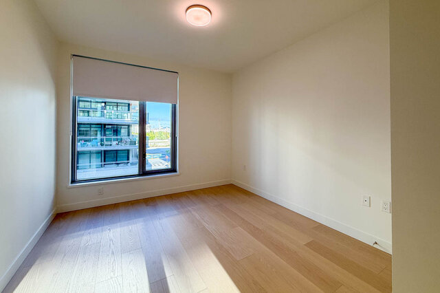 Bright bedroom with hardwood floors and city view. - 406-777 Harbour Way, North Vancouver