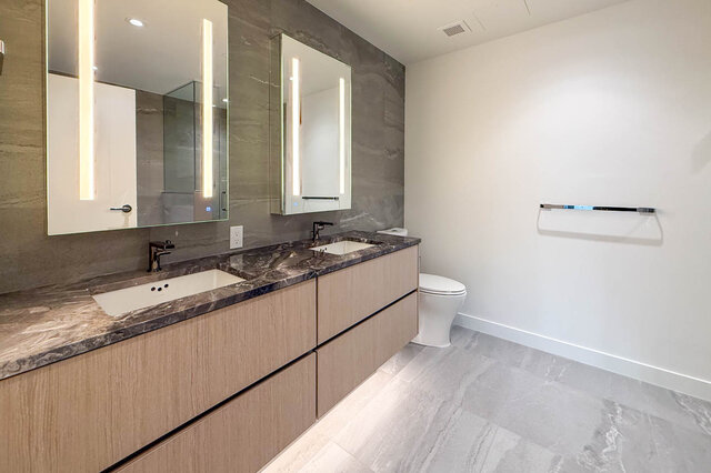 Modern bathroom with marble countertops and under-cabinet lighting. - 406-777 Harbour Way, North Vancouver
