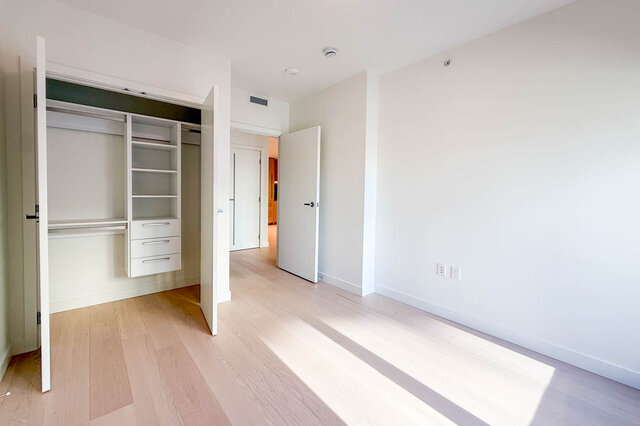 Bedroom with light wood flooring and built-in white closet. - 406-777 Harbour Way, North Vancouver