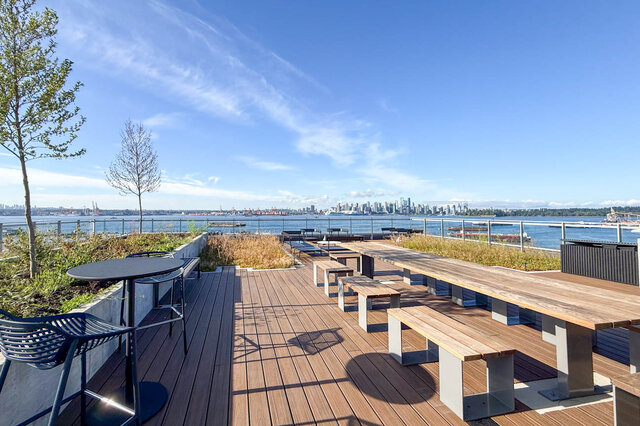 Rooftop deck with wooden tables and benches overlooking city and water. - 406-777 Harbour Way, North Vancouver