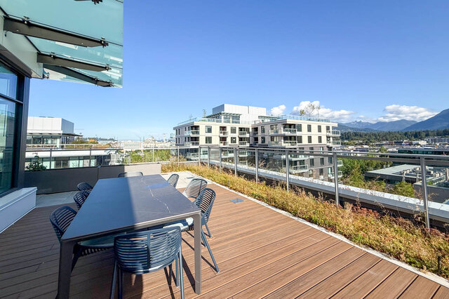 The balcony has a wooden deck, dining table, chairs, city view, and mountain view. - 406-777 Harbour Way, North Vancouver