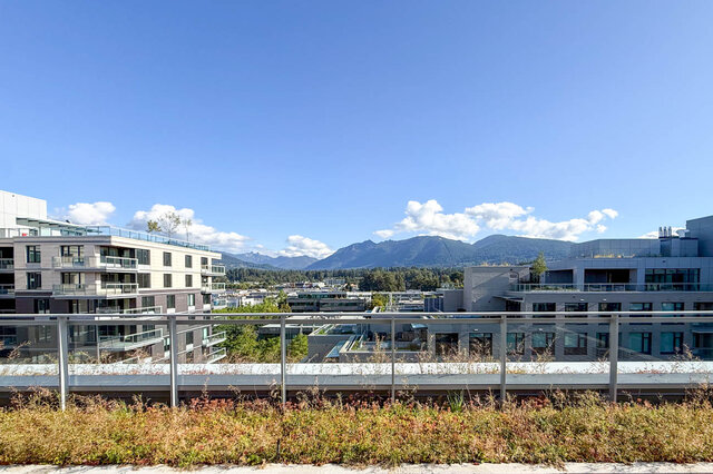 The view shows modern apartment buildings, distant mountains, and a clear blue sky. - 406-777 Harbour Way, North Vancouver