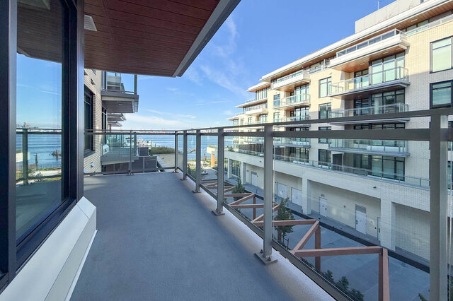 The balcony has a concrete floor, metal and glass railing, and a view of the water and adjacent building. - 406-777 Harbour Way, North Vancouver