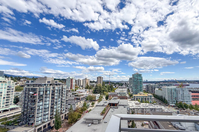 A view of a city skyline with tall buildings, a body of water, and a partly cloudy blue sky - 1601-155 1st Street West, North Vancouver