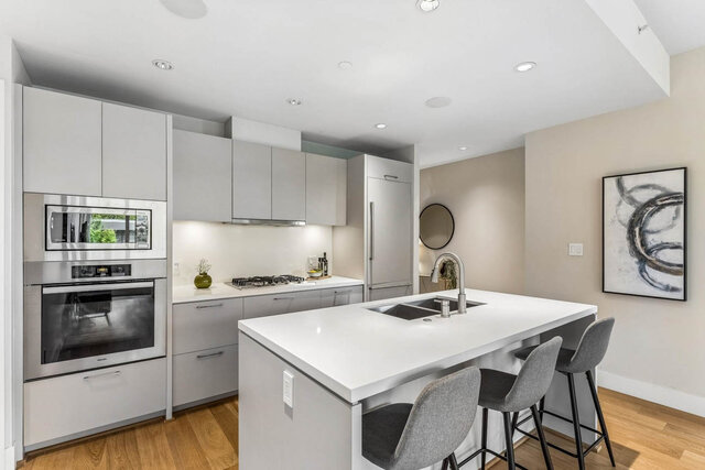 Bright modern kitchen with white quartz countertops and hardwood flooring. - 204-866 Arthur Erickson Place, West Vancouver