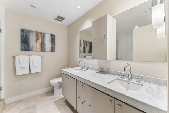 Bright bathroom with marble countertops and dual sinks under a large mirror. - 204-866 Arthur Erickson Place, West Vancouver