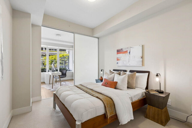 Spacious bedroom with white bedding, wooden bed frame, and bright city view through sliding doors. - 204-866 Arthur Erickson Place, West Vancouver