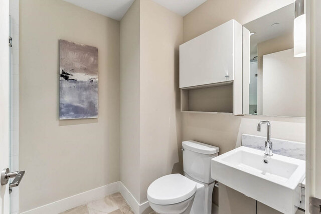 Modern bathroom featuring a white marble sink countertop and sleek white cabinetry. - 204-866 Arthur Erickson Place, West Vancouver