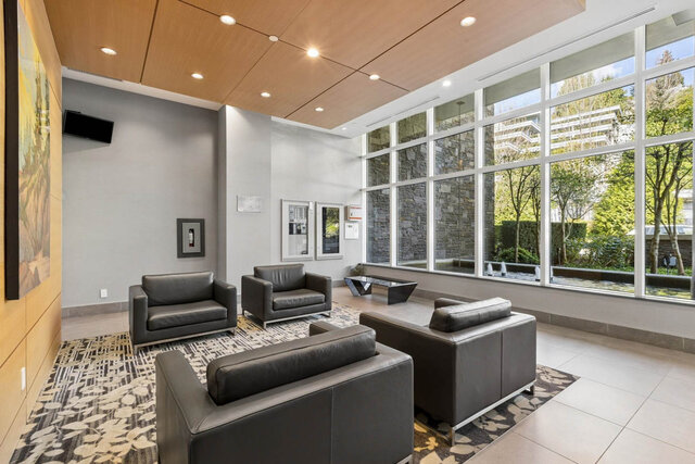 Modern lounge with sleek black leather seating and panoramic greenery views. - 204-866 Arthur Erickson Place, West Vancouver