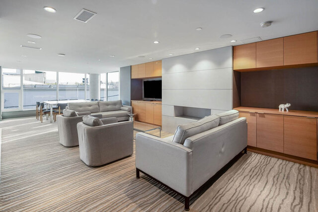 Spacious living room with light gray sofas and waterfront city view in West Vancouver condo. - 204-866 Arthur Erickson Place, West Vancouver