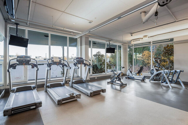 Modern fitness center with three treadmills and stationary bikes overlooking greenery. - 204-866 Arthur Erickson Place, West Vancouver