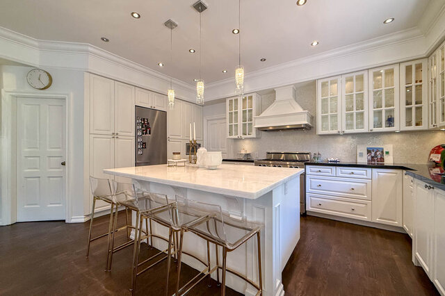 A bright, modern kitchen with white cabinetry, stainless steel appliances, and a marble island. - 1249 Chartwell Place, West Vancouver