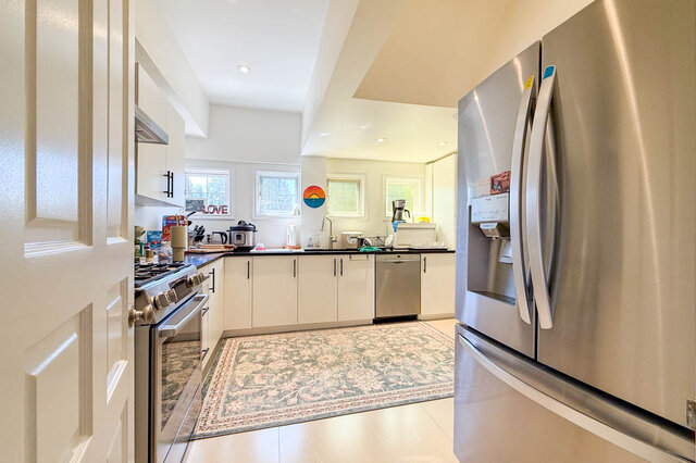 A bright, modern kitchen with stainless steel appliances and white cabinetry - 1249 Chartwell Place, West Vancouver