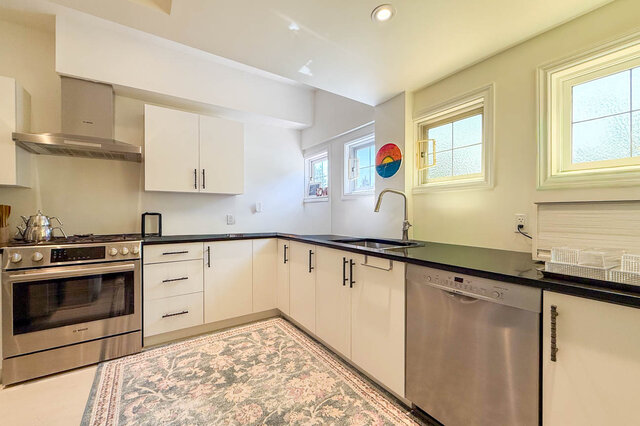 A bright, modern kitchen with stainless steel appliances and white cabinetry - 1249 Chartwell Place, West Vancouver