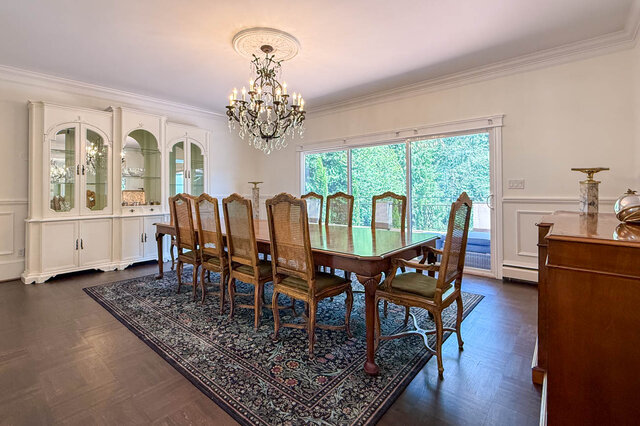 Bright dining area with a wooden table, chairs, and large sliding glass doors overlooking greenery - 1249 Chartwell Place, West Vancouver
