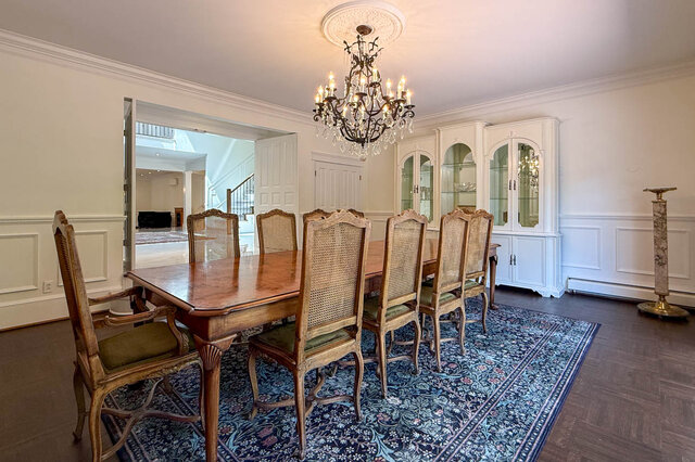 Elegant dining area with wooden table, chairs, chandelier, and built-in cabinets - 1249 Chartwell Place, West Vancouver