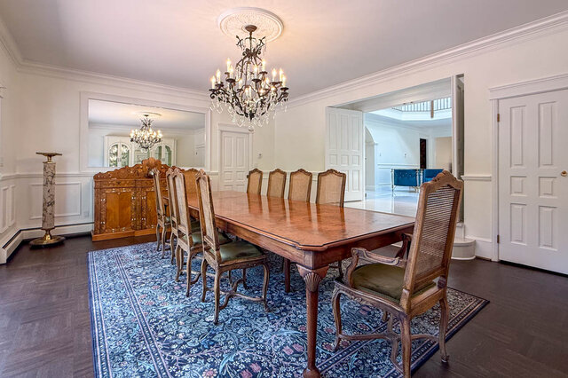 Elegant dining area with a large wooden table, crystal chandelier, and ornate cabinetry - 1249 Chartwell Place, West Vancouver