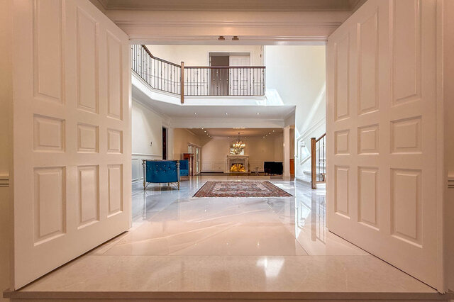 Grand living room with marble floors, fireplace, chandelier, and balcony. - 1249 Chartwell Place, West Vancouver