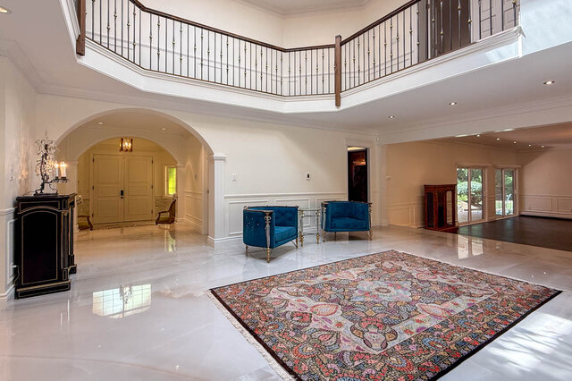 A spacious living room with marble flooring, a grand staircase, and blue velvet chairs. - 1249 Chartwell Place, West Vancouver