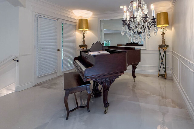 A bright living room featuring a grand piano, crystal chandelier, and French doors with shutters. - 1249 Chartwell Place, West Vancouver