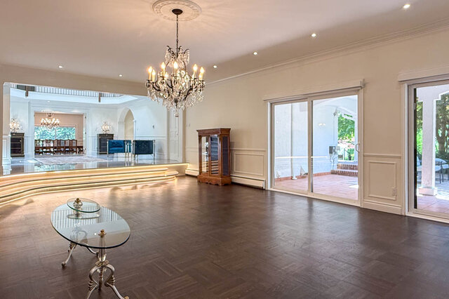 Spacious living room with hardwood floors, a crystal chandelier, and large sliding glass doors. - 1249 Chartwell Place, West Vancouver