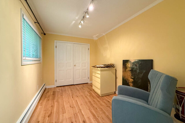 A bright living room with hardwood floors, a window with blinds, and a blue armchair. - 1249 Chartwell Place, West Vancouver