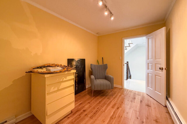 A well-lit living room with yellow walls, hardwood floors, and a gray armchair. - 1249 Chartwell Place, West Vancouver