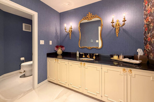 A stylish bathroom with blue walls, gold accents, and white cabinetry - 1249 Chartwell Place, West Vancouver