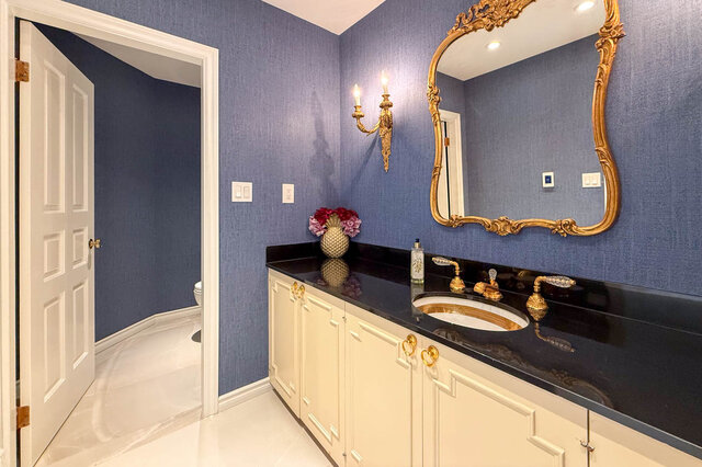 Elegant bathroom with blue walls, gold accents, and a black countertop - 1249 Chartwell Place, West Vancouver