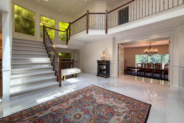 Spacious living room with grand staircase, fireplace, and large area rug under bright natural light - 1249 Chartwell Place, West Vancouver