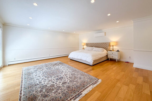 A spacious bedroom with hardwood floors, a large area rug, and a tufted headboard - 1249 Chartwell Place, West Vancouver