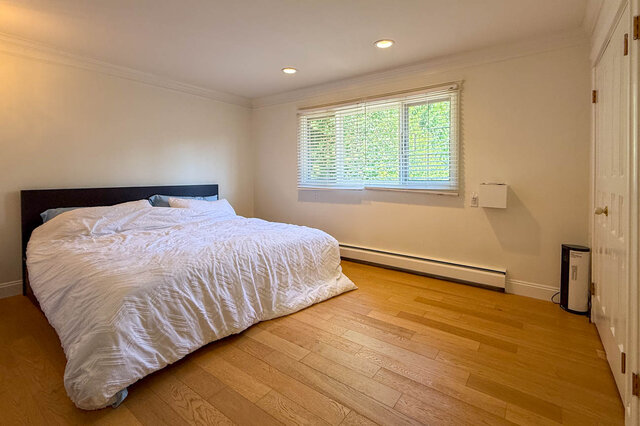A bright bedroom with hardwood floors and a bed. - 1249 Chartwell Place, West Vancouver