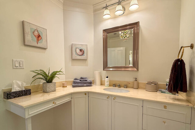 A bright bathroom with marble countertops and decorative seashell art. - 1249 Chartwell Place, West Vancouver