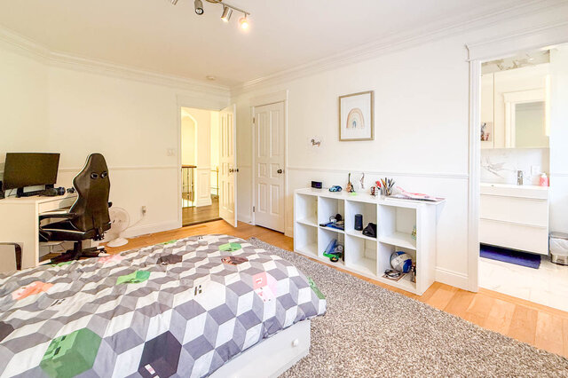 Bright bedroom with hardwood floors, desk area, and adjacent bathroom. - 1249 Chartwell Place, West Vancouver