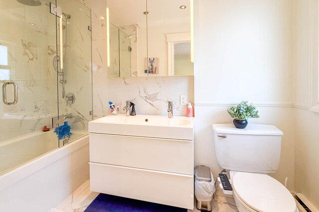 Modern bathroom with glass shower, white vanity, and toilet with plant. - 1249 Chartwell Place, West Vancouver