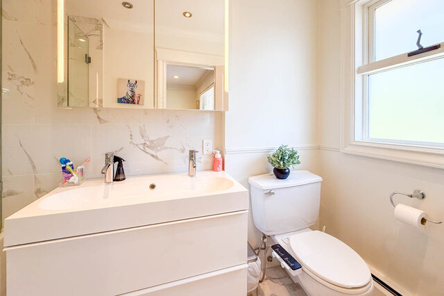 A bright, modern bathroom with a white vanity, toilet, and window - 1249 Chartwell Place, West Vancouver