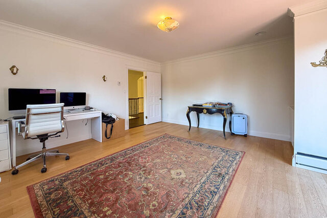 A well-lit den with hardwood floors, a large area rug, and dual computer monitors - 1249 Chartwell Place, West Vancouver