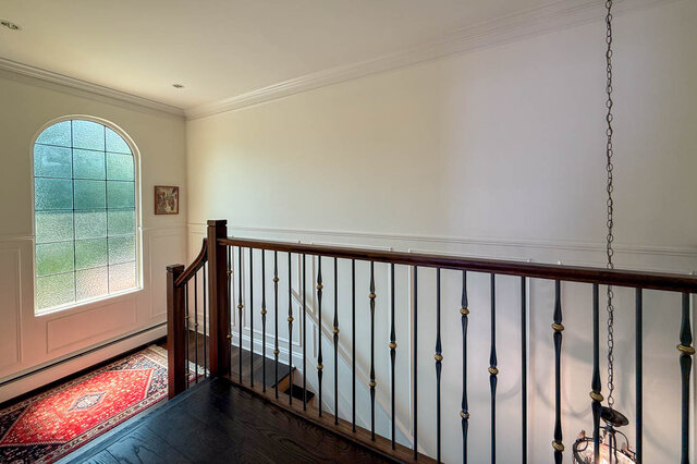 Bright interior hallway with dark hardwood floors, an arched window, and wainscoting - 1249 Chartwell Place, West Vancouver