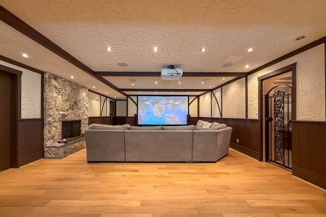Spacious den with large sectional sofa, projector setup, and stone fireplace. - 1249 Chartwell Place, West Vancouver