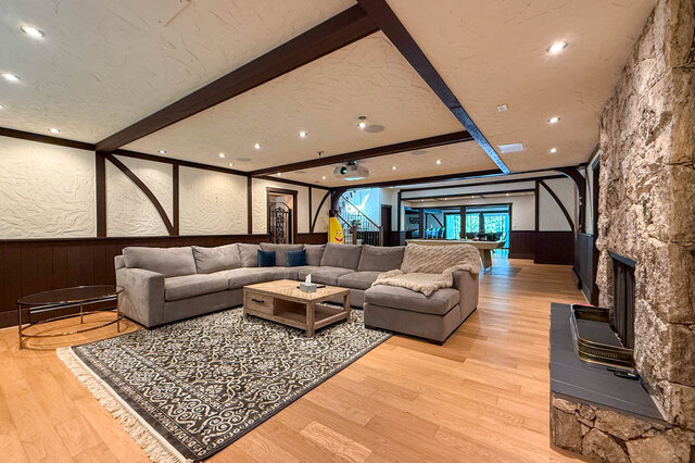 Spacious living room with hardwood floors, stone fireplace, and exposed beams - 1249 Chartwell Place, West Vancouver