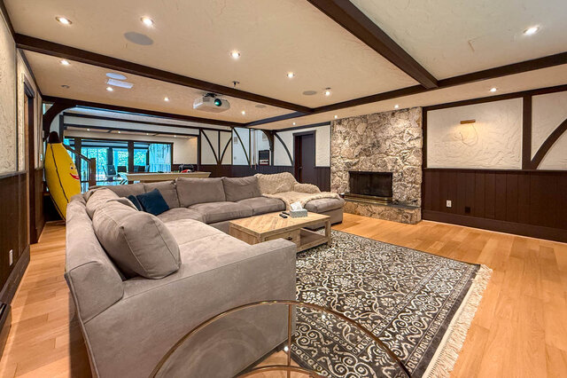 A spacious living room with hardwood floors, a stone fireplace, and a large sectional sofa. - 1249 Chartwell Place, West Vancouver